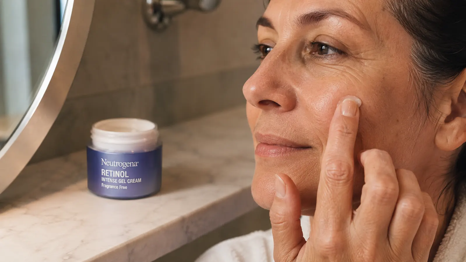 Close-up of a hand smoothing a pea-sized amount of cream across a cheek after cleansing